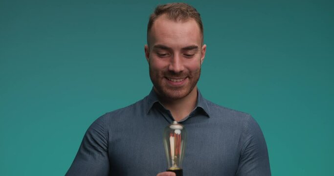young casual man holding a lightbulb and feeling excited for his new ideea then having a lack of inspiration and feeling sad