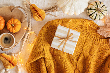 Autumn flat lay composition. Warm comfort sweater, pumpkins, gift boxes, dried leaves. Thanksgiving, fall, slow living concept. Top view, copy space