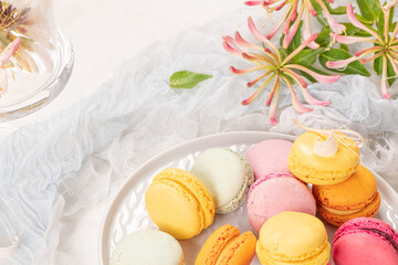 Colorful french macaroon cakes. Macaroons with jasmine flowers on white table background. Selective focus