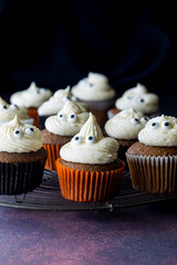 Pumpkin spice cupcakes on a metal cooling rack, against a black background.