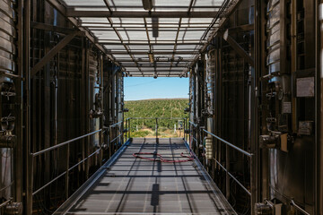 Tanks for wine fermentation in the modern winery on background of vineyard