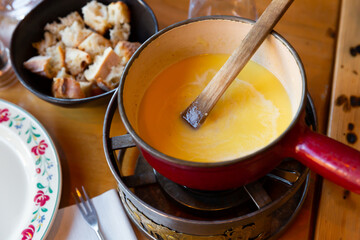 French variation of Swiss dish fondue, Fondue Savoyarde, preparing on table.