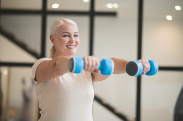 Joyful woman working out with hand weights