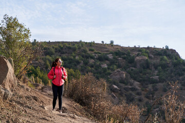 Obraz premium young woman with red jacket and backpack, descending the mountain in the middle of the Andes Mountains of Chile