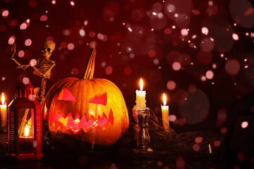 Carved Halloween pumpkin with skeleton, lantern and burning candles on dark background