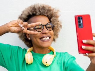 Smiling young african american woman with afro hair and headphones taking a selfie