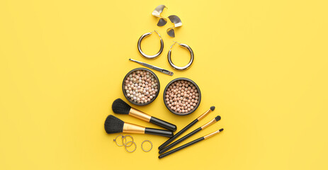 Creative Christmas tree made of makeup cosmetics, brushes and jewelry on yellow background