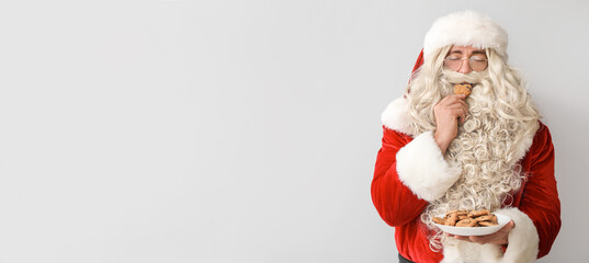 Santa Claus eating tasty cookies on light background with space for text