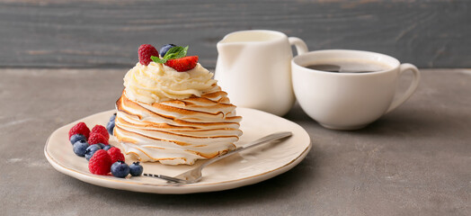 Plate with tasty Pavlova cake with tea on grey background
