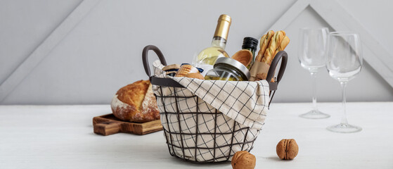 Gift basket with products and wine on table