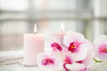 Fototapeta na wymiar Orchids and burning aromatic candles on spa salon