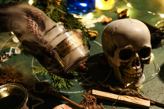 Witch Holding Jar With Frog Bones On Wizard Table