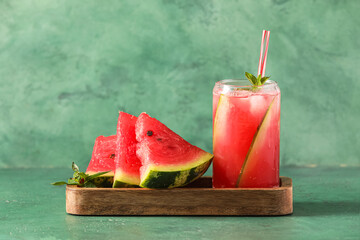 Wooden board with glass of cold watermelon fresh on green background