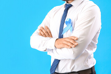 Businessman with awareness ribbon on blue background. Prostate cancer concept