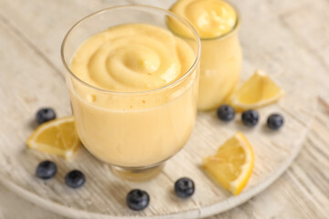 Glass bowl of tasty vanilla pudding on light wooden table, closeup