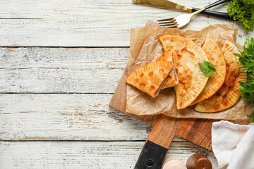 Board with tasty chebureks on light wooden table