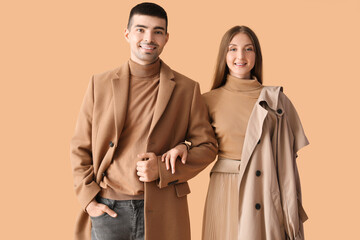 Fashionable young couple in autumn clothes on beige background
