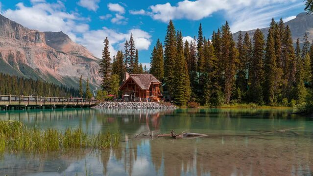 4K time-lapse UHD video of scenery of wooden house with rocky mountains and cloudy blowing reflection on Emerald Lake,a Glacial Lake at Yoho national park in the mountain parks of the Canadian Rocky
