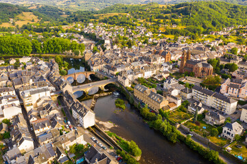 Scenic aerial view of French commune of Espalion on banks of Lot river with medieval Parish Church on summer day, Aveyron department .