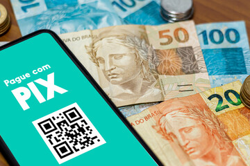Pix on smartphone screen with multiple coins around. Pix is the new payment and transfer system of the Brazilian and Brazilian government.