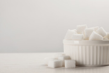 Bowl with sugar cubes served on white table. Space for text