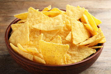 Bowl with tasty tortilla chips (nachos) on wooden table