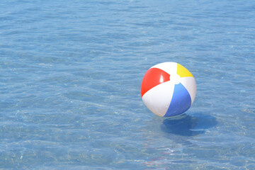 Colorful beach ball floating in sea on sunny day, space for text
