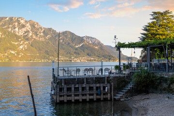 cA small outdoor cafe with patio at the peaceful fishing village of Pescallo Italy, near the town of Bellagio on Lake Como in Northern Italy at sunset.