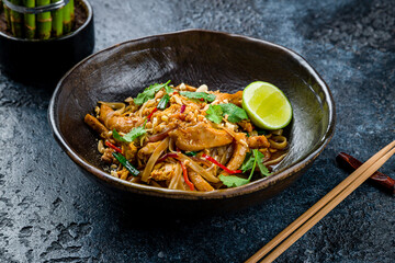 pad thai noodles with chicken on dark stone table - 536861050
