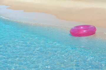 Bright inflatable ring on sandy beach near sea. Space for text