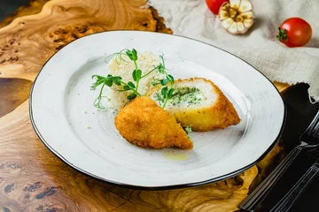 Tuinposter chicken Kiev cutlet with couscous on wooden table © bbivirys