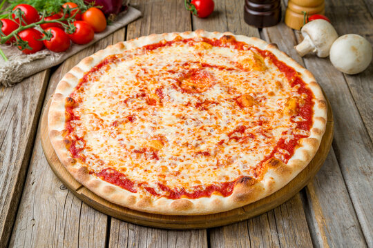 Italian pizza Margherita, cheese, tomato sauce, on wooden table close up