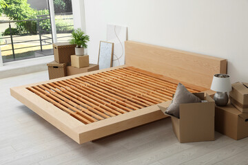 New wooden bed frame, moving boxes and decor elements indoors