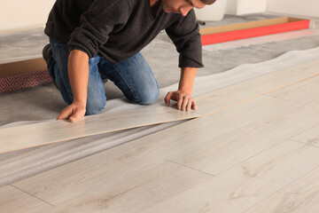 Professional worker installing new laminate flooring, closeup