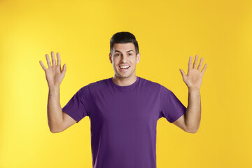 Fototapeta premium Cheerful man waving to say hello on yellow background