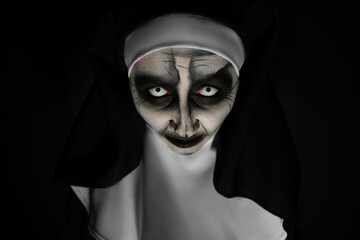 Portrait of scary devilish nun on black background. Halloween party look