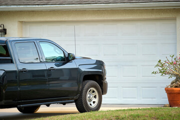 Car parked in front of wide garage double door on concrete driveway of new modern american house