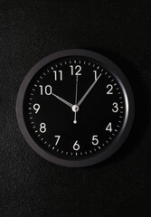 black modern clock hanging on a black wall