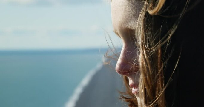 close up caucasian teenage girl looking at the horizon from a black sand beach in iceland
