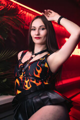 Fototapeta na wymiar Beautiful dancer in a black bodysuit with fire posing in a nightclub. Party concept