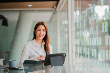 Successful attractive Asian businesswoman works from home with a tablet.