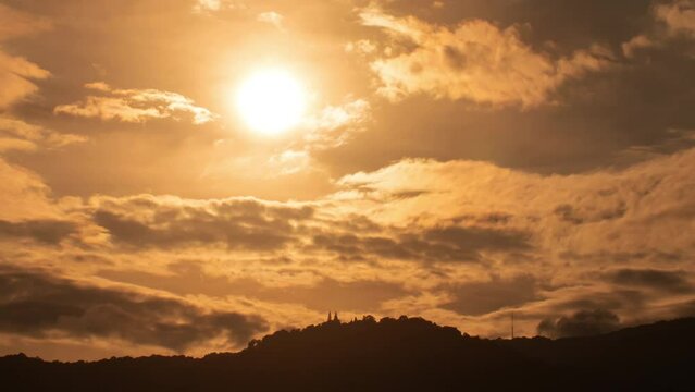 Time lapse of dramatic sunset over a mountain with orange sky in a sunny day.