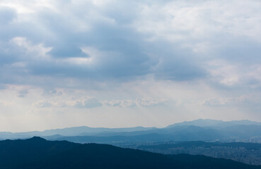 Obraz premium A ridge in the foreground under a majestic sky. A faint sunlight shining through the clouds.
