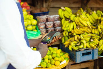 close up hand of an african male trader paying with a terminal machine