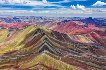 Luftaufnahme der gesamten Regenbogenberge in Peru mit Vinicunca im Zentrum und dem Roten Tal im Hintergrund.
