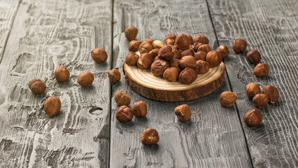 Hazelnuts scattered on a wooden stand on a wooden table.