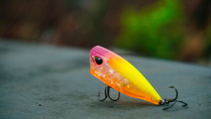 Fototapeta na wymiar Artificial lure made from plastic for fishing by popping. Popper lure with hook with selective focus - Artificial lure with the shape of minnow