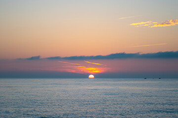 Evening sunset over the sea on the horizon among rare clouds.
