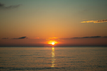Evening sunset over the sea on the horizon among rare clouds.