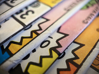 Closeup view of an old comic book collection stacked in a pile creates colorful background paper texture with abstract shapes
